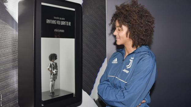 Sara Gama regarde sa poupée barbie