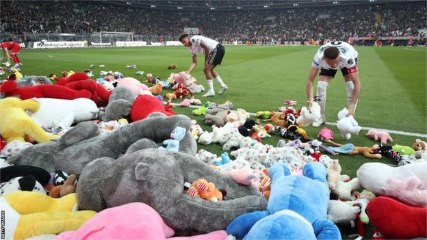 Les joueurs dégagent le terrain après que Besiktas ait jeté des ours en peluche sur le terrain pour soutenir les enfants victimes du tremblement de terre