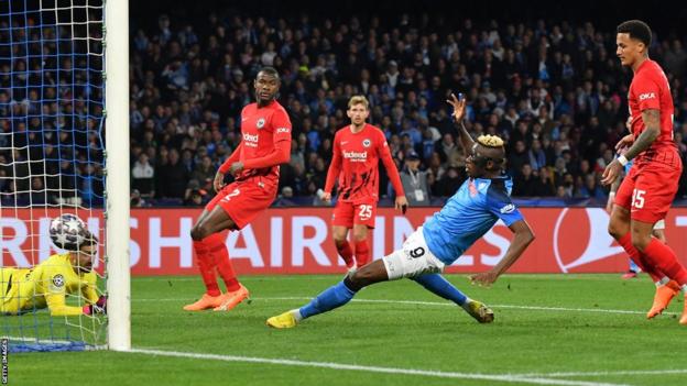 L'attaquant nigérian de Napoli Victor Osimhen (C) marque le deuxième but de son équipe devant le gardien de but allemand de Francfort Kevin Trapp (L) lors de la ronde de 16 de la Ligue des champions de l'UEFA, match de football de deuxième jambe entre SSC Napoli et Eintracht Frankfurt au stade Diego-Maradona de Naples le 15 mars 2023
